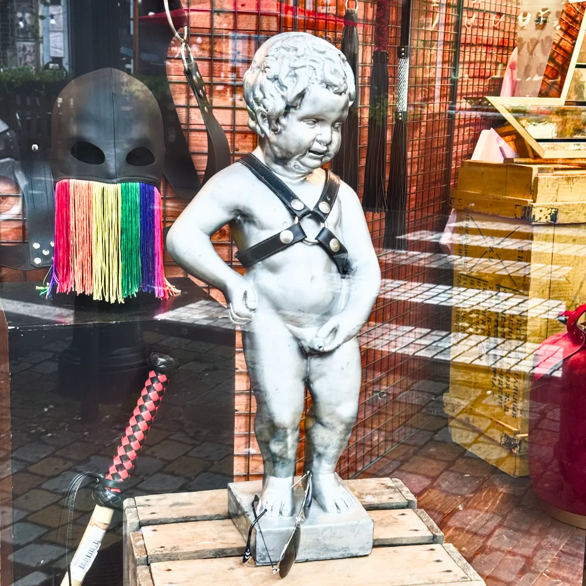 Piss child sculpture replica in a gay fetish store wearing a harness